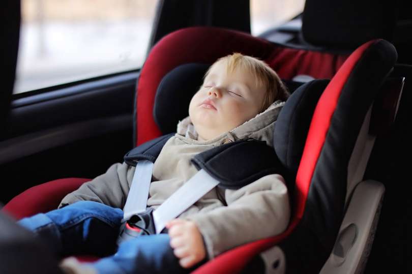 тепло одетый ребенок спит в машине